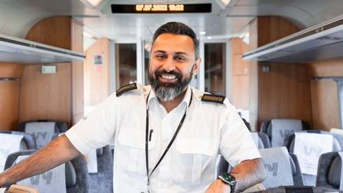 Chief conductor Ali stands in the aisle of the train and smiles