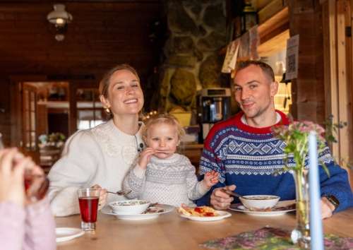 Mother, father and children sitting at a table eating in a cabin.