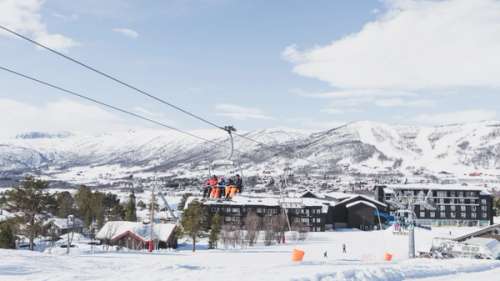 People in the ski lift heading up the slope with Vestlia in the background.