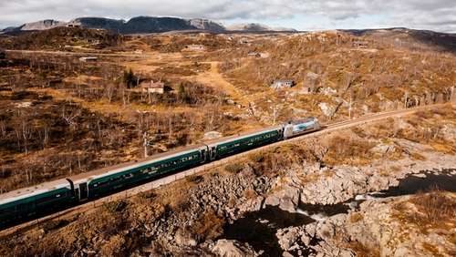 Train driving through autumnal mountain landscape