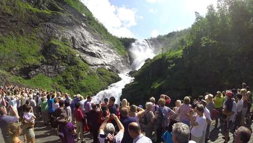 People standing watching a large waterfall.