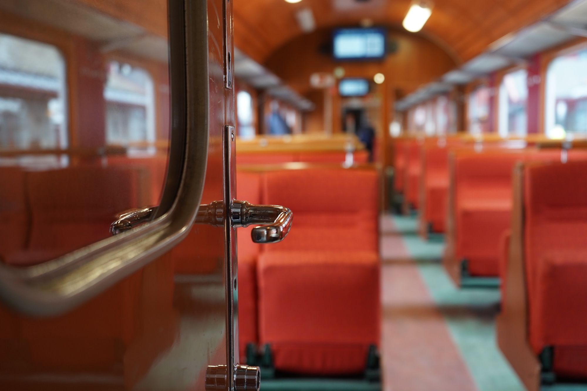 The innside of a train carriage with red seats.
