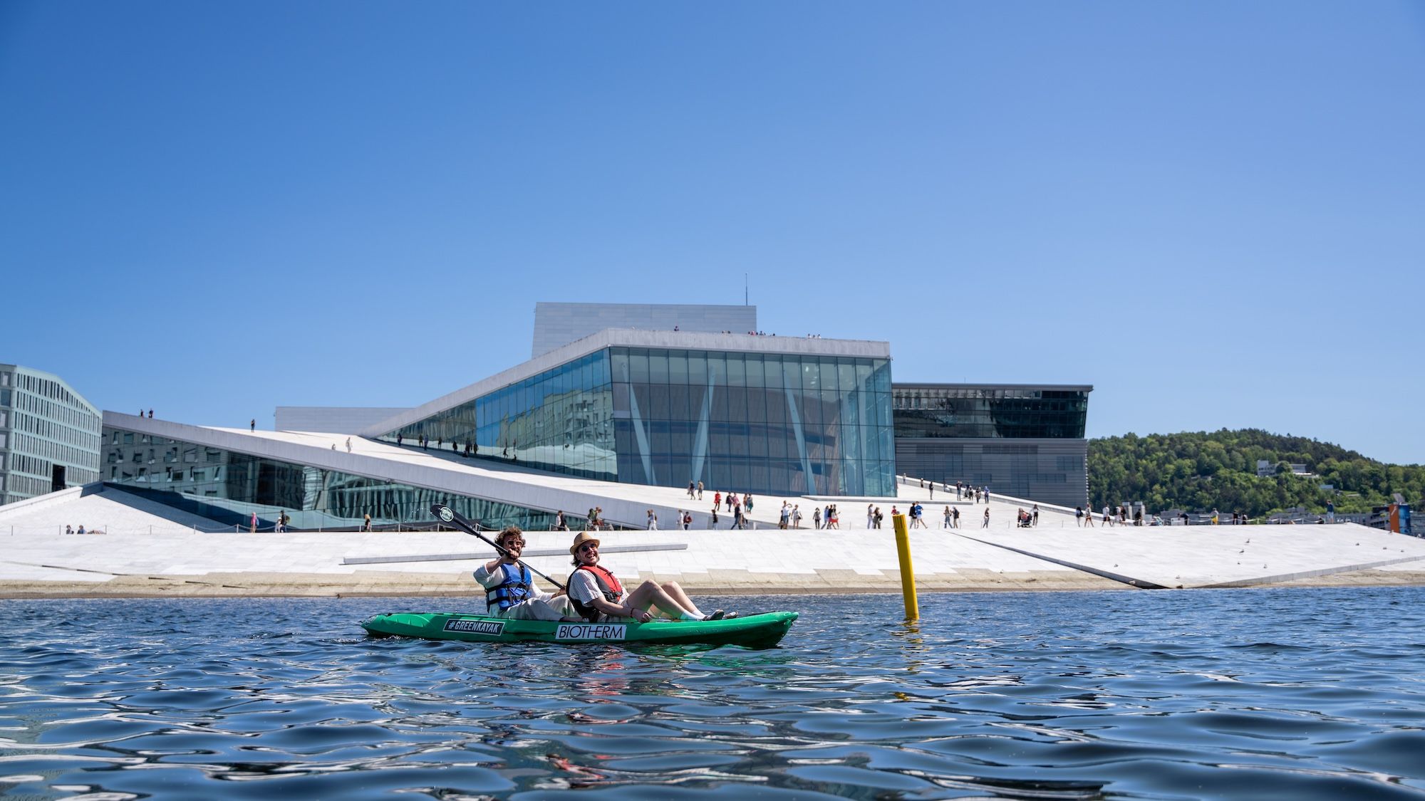 Two friends in a kayak outside the Oslo Opera House