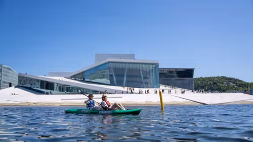 Two friends in a kayak outside the Oslo Opera House