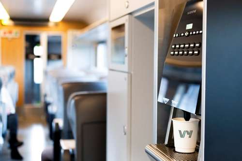 Kaffemaskin i Pluss-vogn med togseter i bakgrunnen