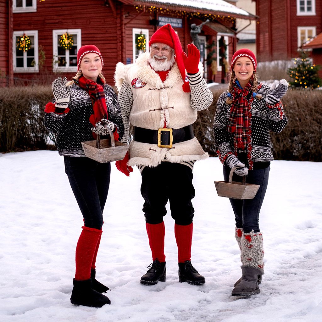To jenter og en mann kledd ut som nisser på Hadeland Glassverk.