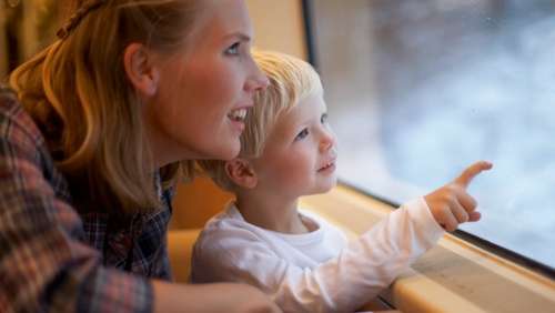 Ung mor med liten gutt ser ut av togvinduet