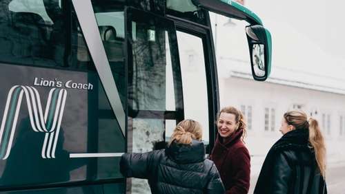 Three people wearing winter jackets getting on the bus.