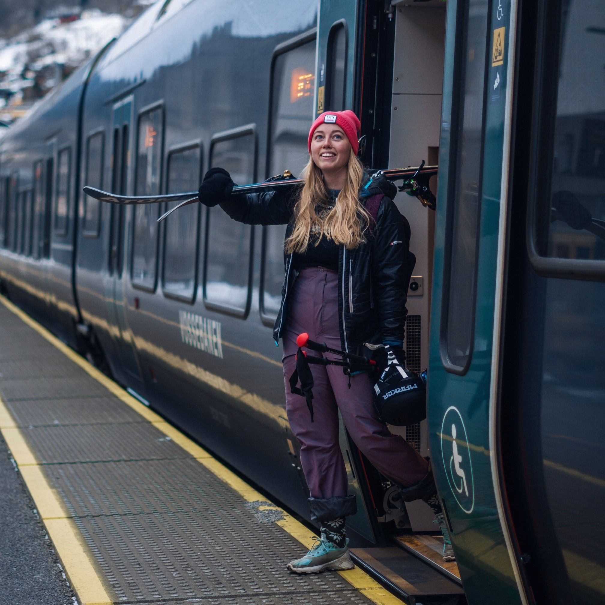 Kvinne med slalåmutstyr på vei ut av toget på Voss stasjon