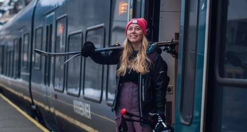 Kvinne med slalåmutstyr på vei ut av toget på Voss stasjon