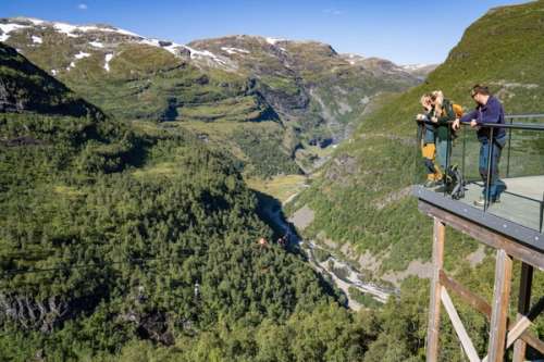 Tre personer ser utover utsikten og to personer som kjører zipline