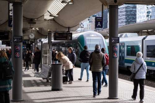 Mennesker som går og står på platformen, Vy-tog i bakgrunnen.