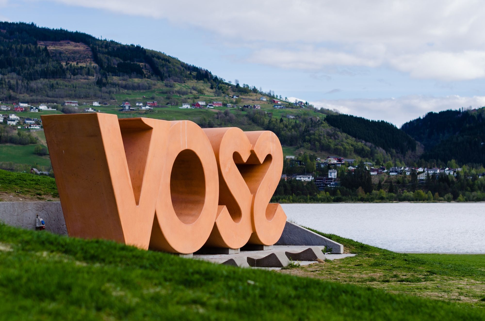 Large sign saying Voss, placed in a green landscape