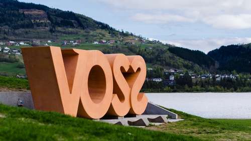 Large sign saying Voss, placed in a green landscape