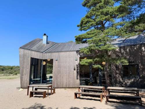 Storesand beach offers both a catering outlet and toilet facilities. It is a modern building with several picnic benches in front of it.