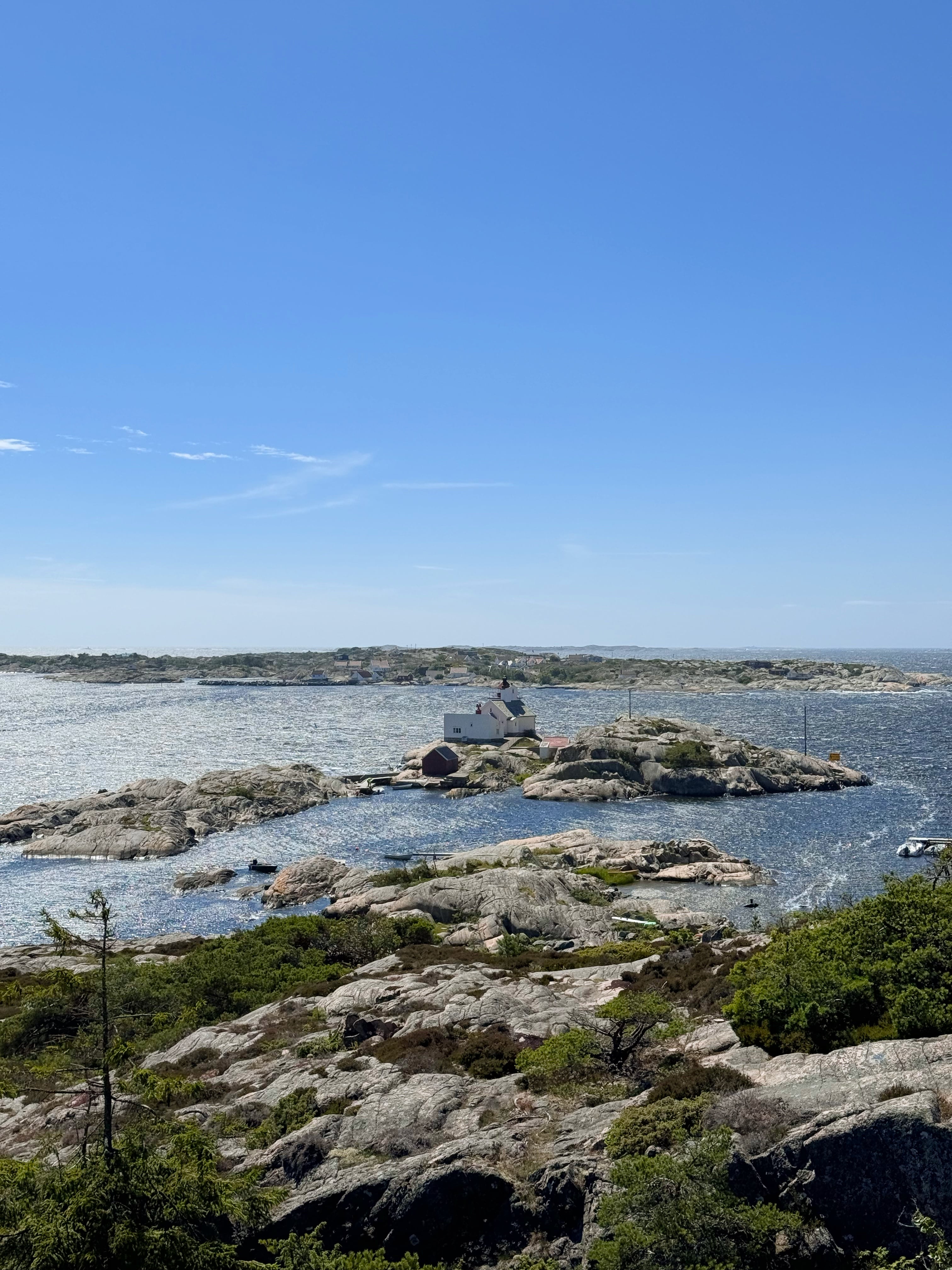 Utsikt over skjærgården med blå himmel og hav. Et hvitt hus ligger helt ute ved skjærene.