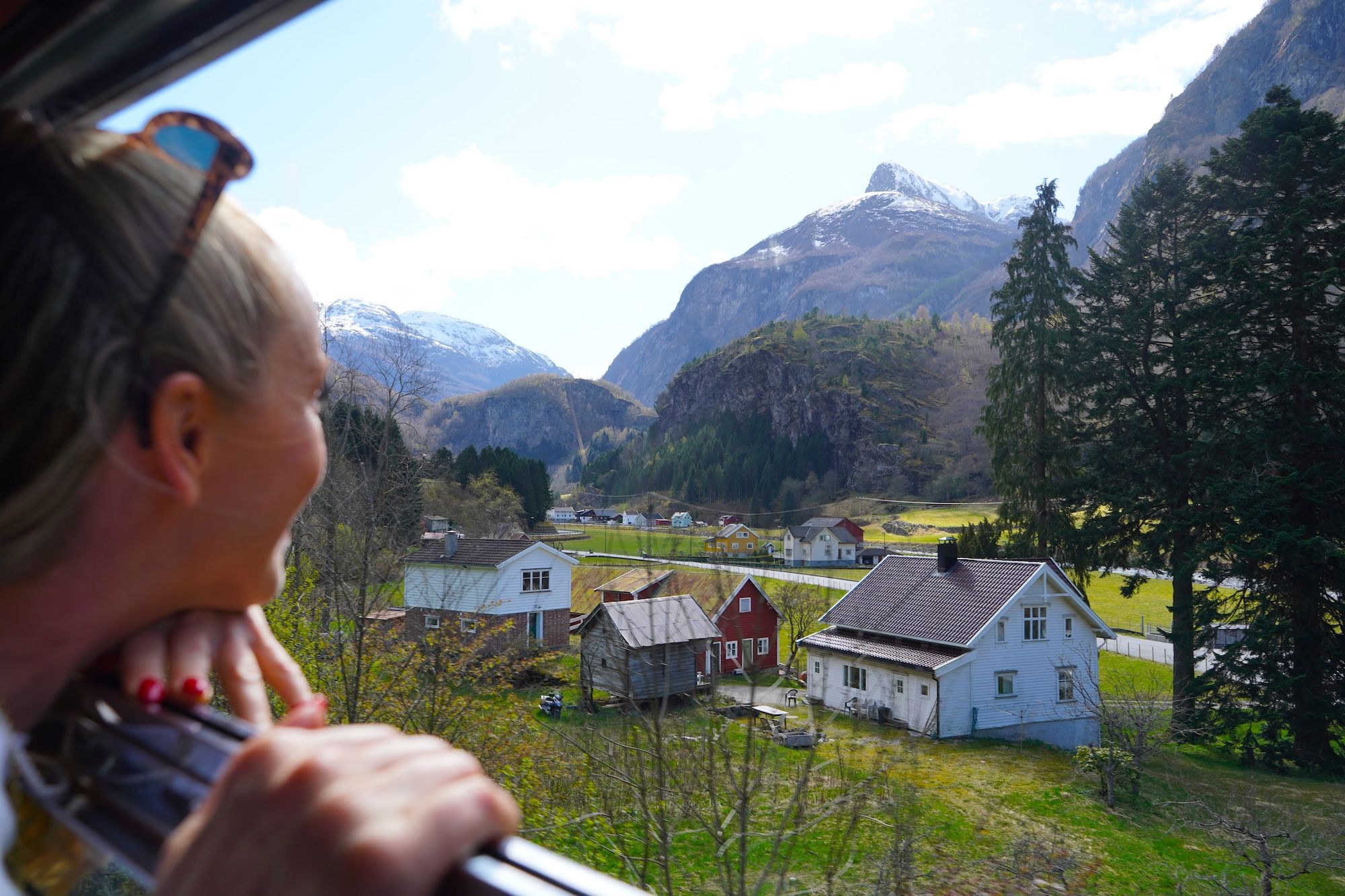 Woman looking out of the train window at houses and mountains.
