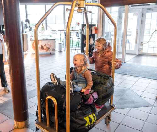 Two children playing with a luggage trolley.