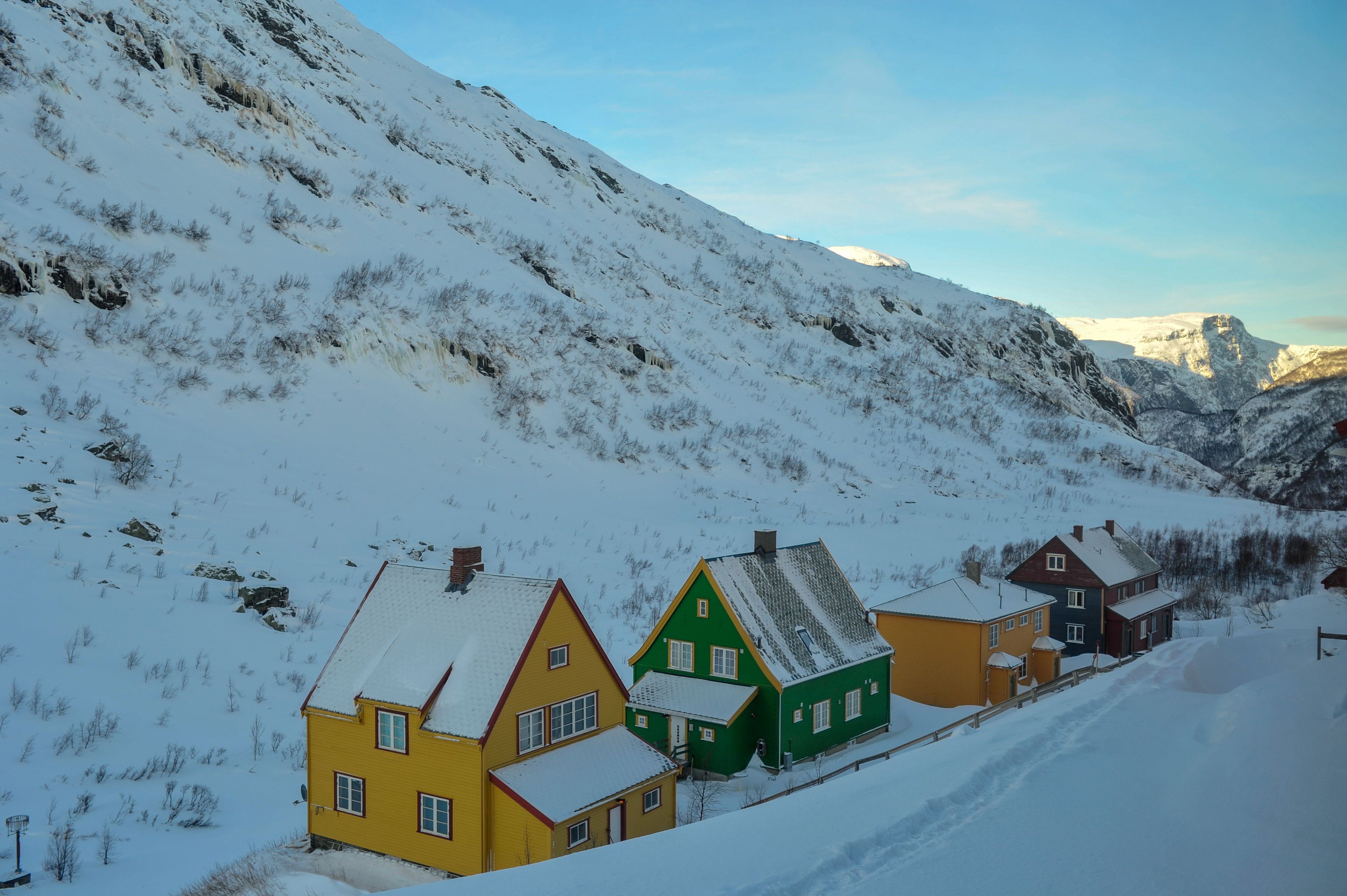 Fargerike hus i Myrdal, omgitt av snødekte fjell.