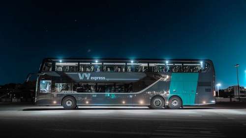 A double decker bus parked in the night.