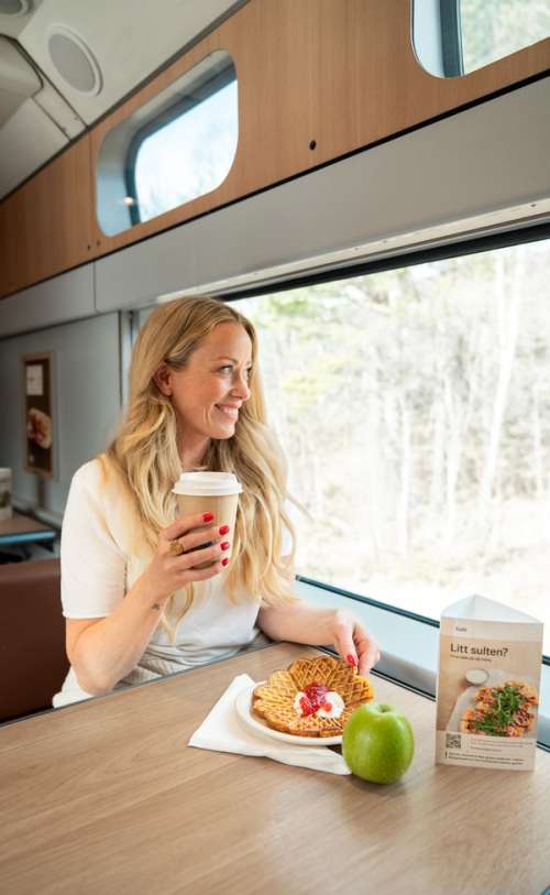 Woman eating a waffle on the train.