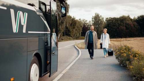Mann og dame på holdeplass, på vei for å gå inn i bussen