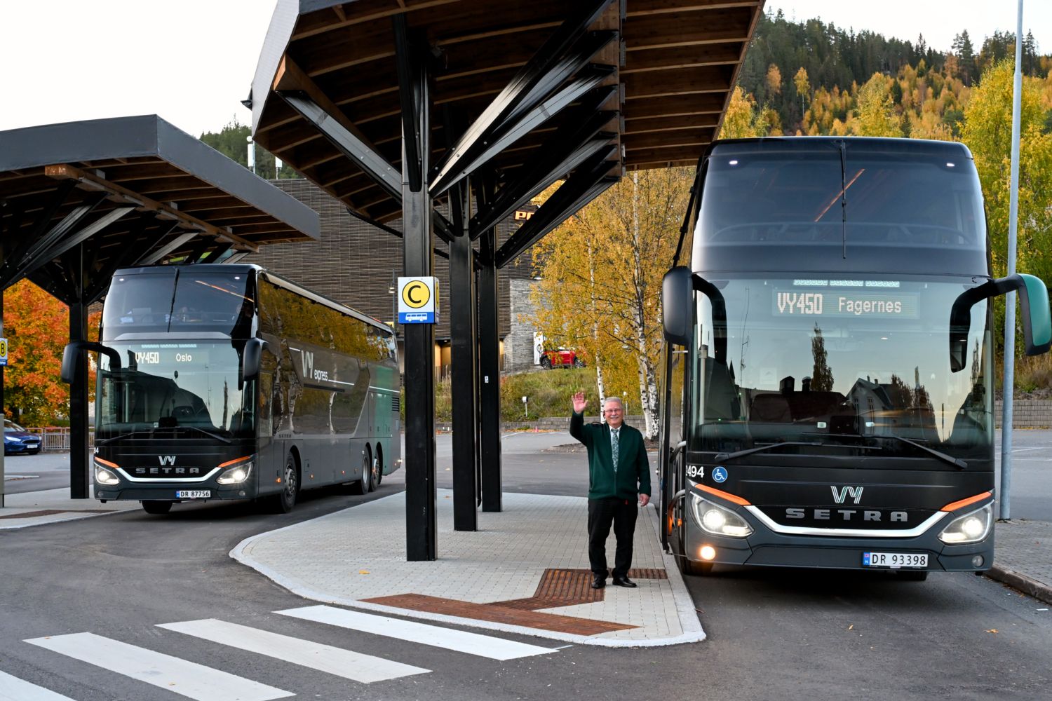 To Vy-busser på Fagernes stasjon og en bussjåfør ved siden av bussen som vinker.