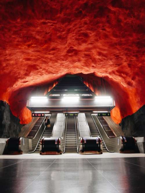 Escalators in an underground station with a red ceiling