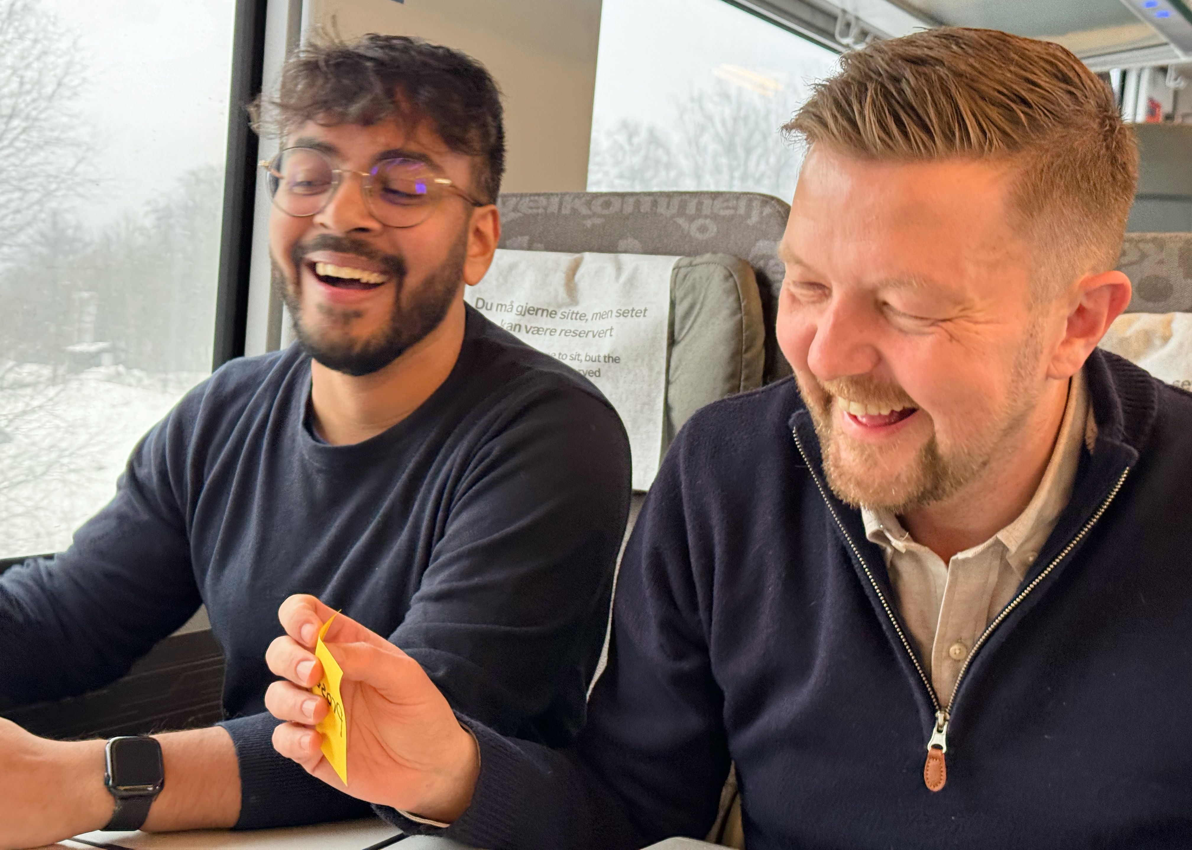 En gruppe kollegaer sitter i sofaer i en kupé og har en workshop