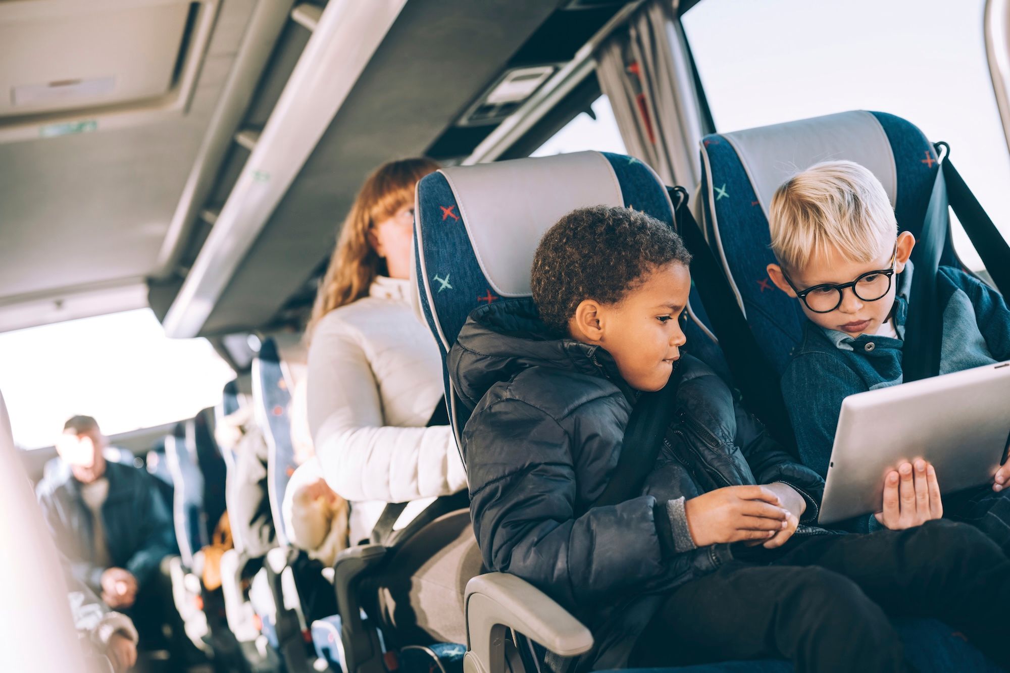 Two children on the bus watching a tablet.