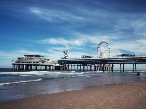 Scheveningen Pier som er bygget ut i vannet. Sandstrand og vann.