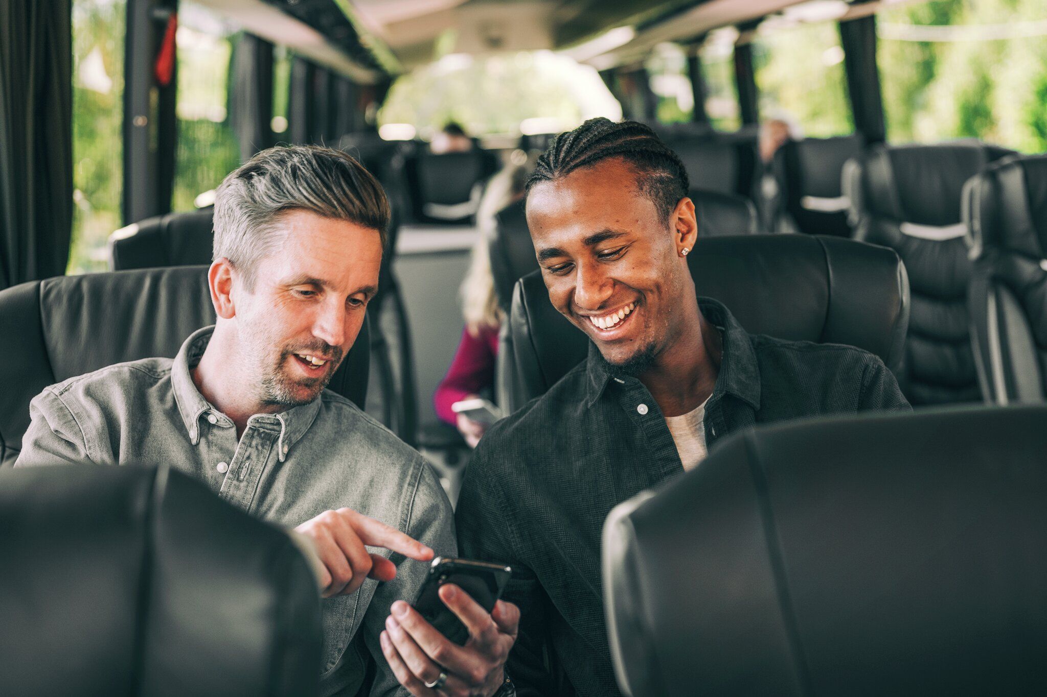 To menn på bussen ser på telefonen sammen