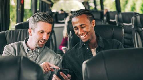 To menn på bussen ser på telefonen sammen