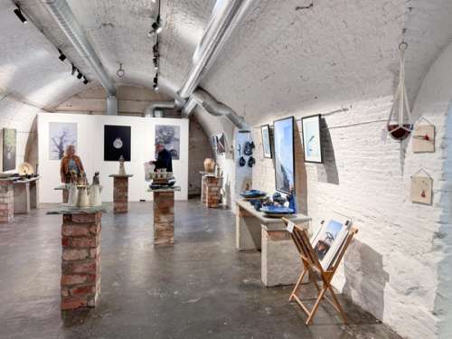 Folk koser seg ute på uteserveringa til Café Magenta. Hos kunstgalleriet og verkstaden Galleri B5 kan du sjå kunstverk av keramikk, måleri og fotografi.