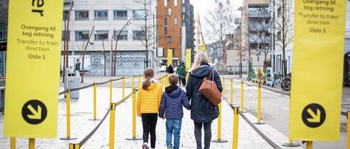 Kvinne med to barn går nedover sluse for buss for tog på Asker stasjon