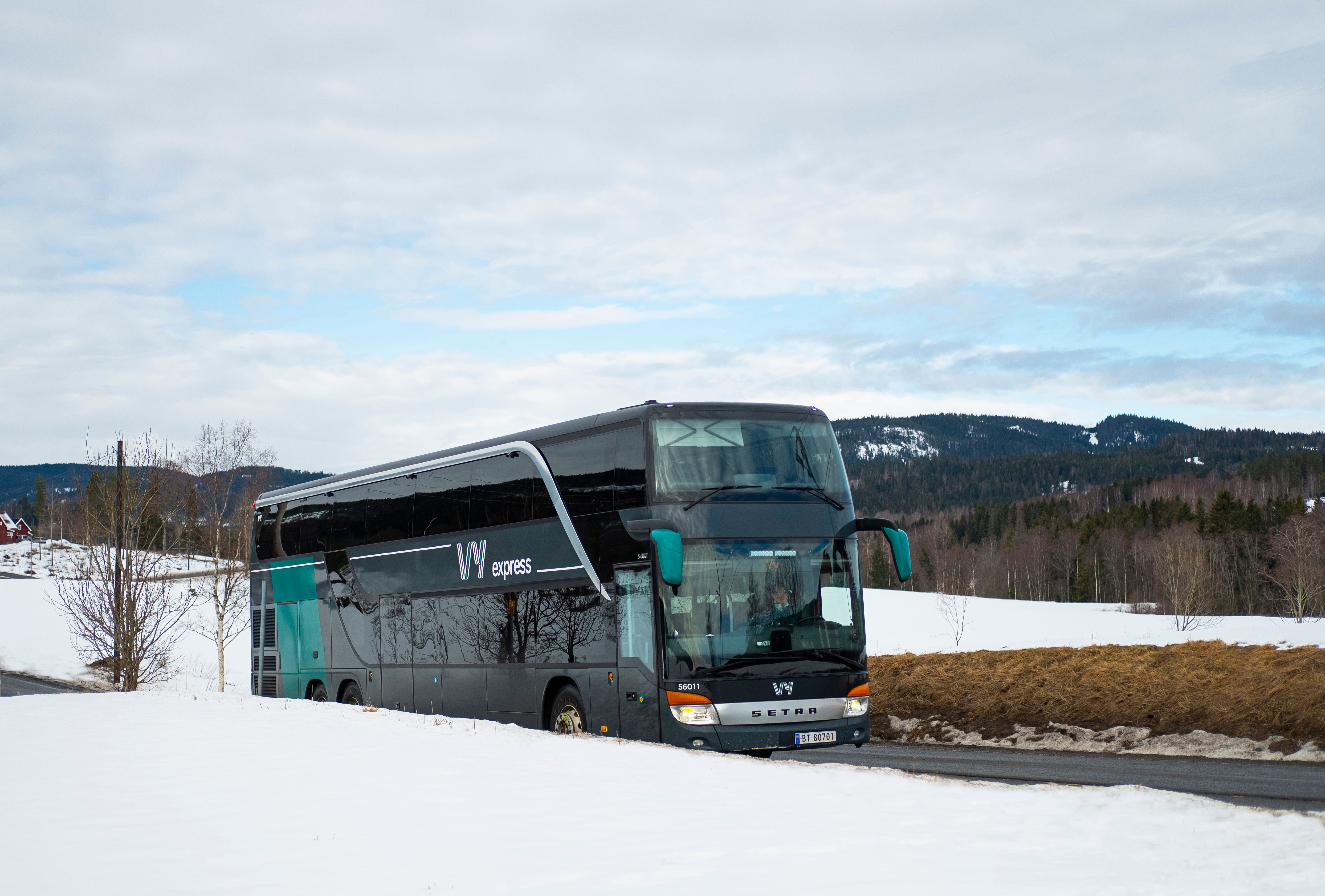 Bus driving through a winter landscape with snow.
