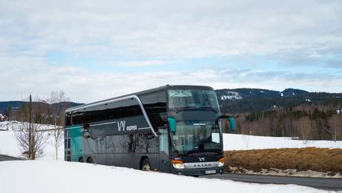 Bus driving through a winter landscape with snow.