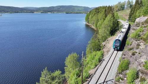 Tog køyrer forbi eit vatn i fint vêr