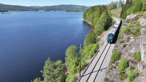 Tog køyrer forbi vatn i fint vêr