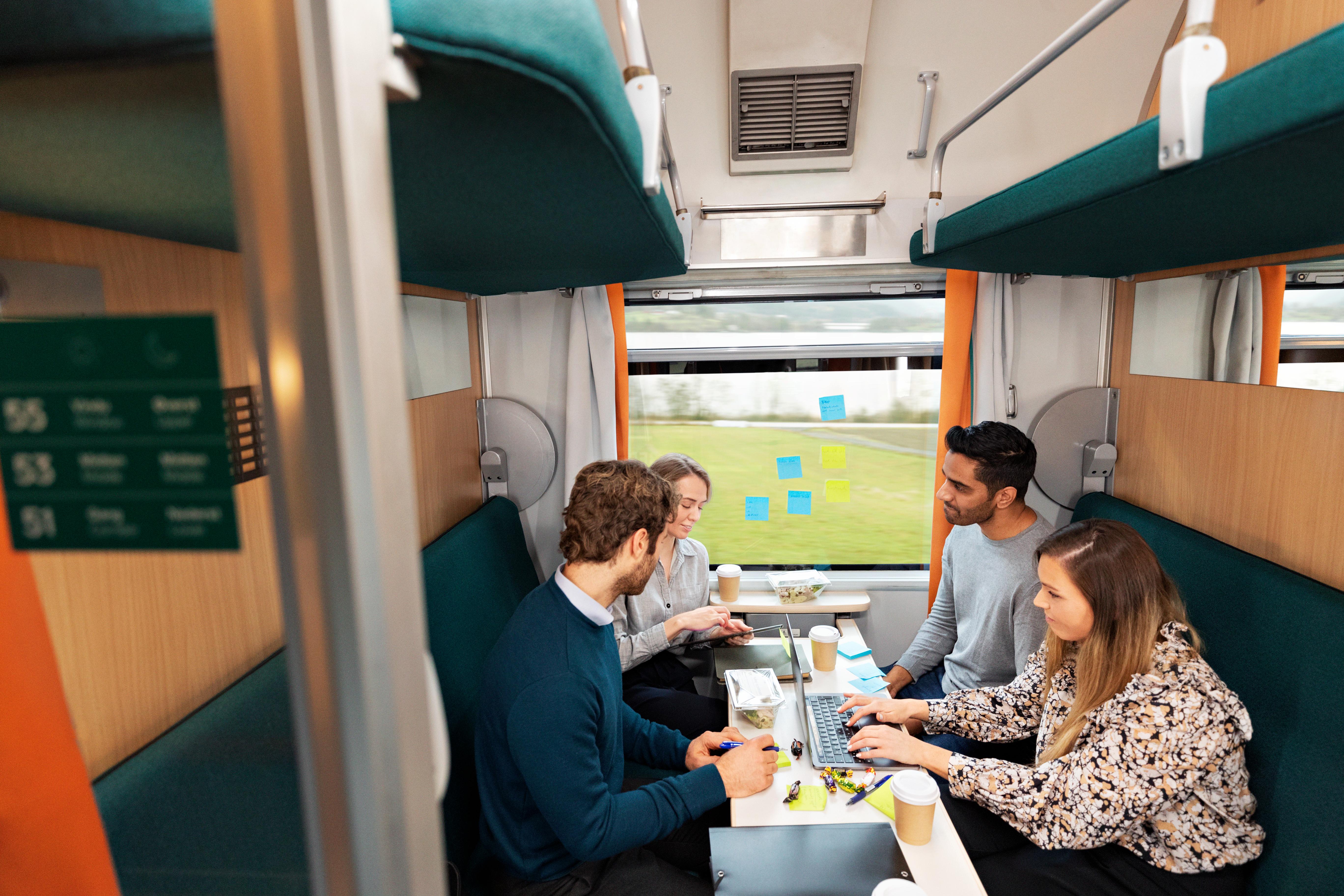 En gruppe kollegaer sitter i sofaer i en kupé og har en workshop