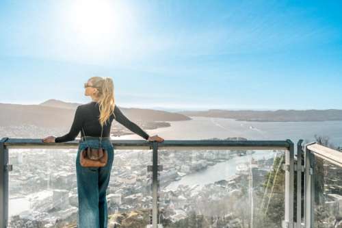 Woman stands looking down on Bergen from the top of the Fløibanen funicular.