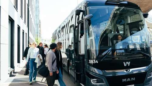 En turbuss fra Vy som står parkert med folk på vei inn i bussen.