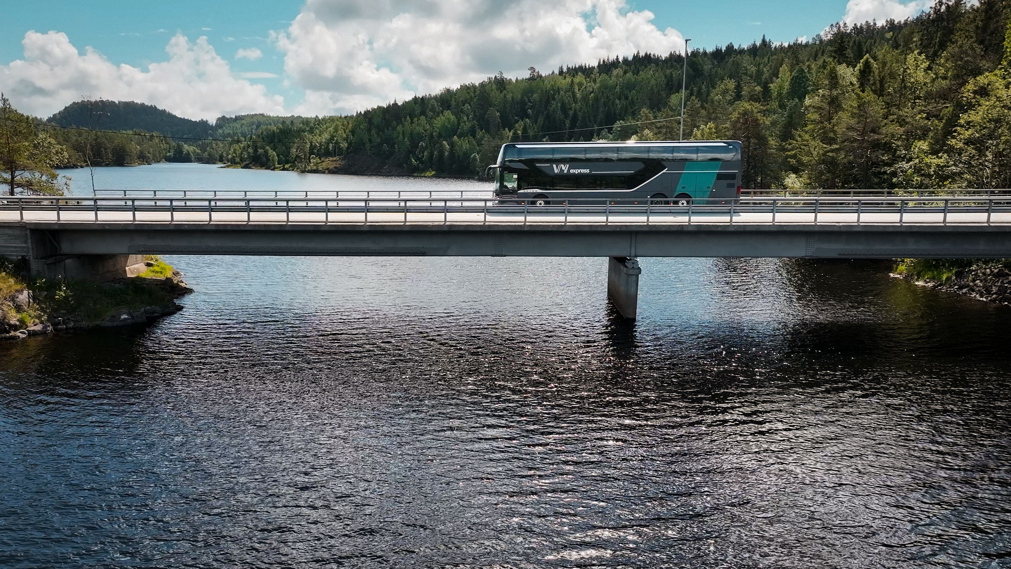 En Vy-buss som kjører over en bro ved kysten.