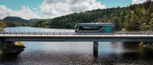 En Vy-buss som kjører over en bro ved kysten.