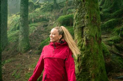 Woman in a red jacket out walking in the woods.