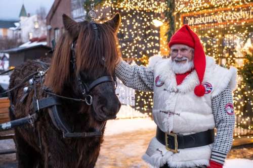 En mann kledd ut som julenisse ved siden av en hest.