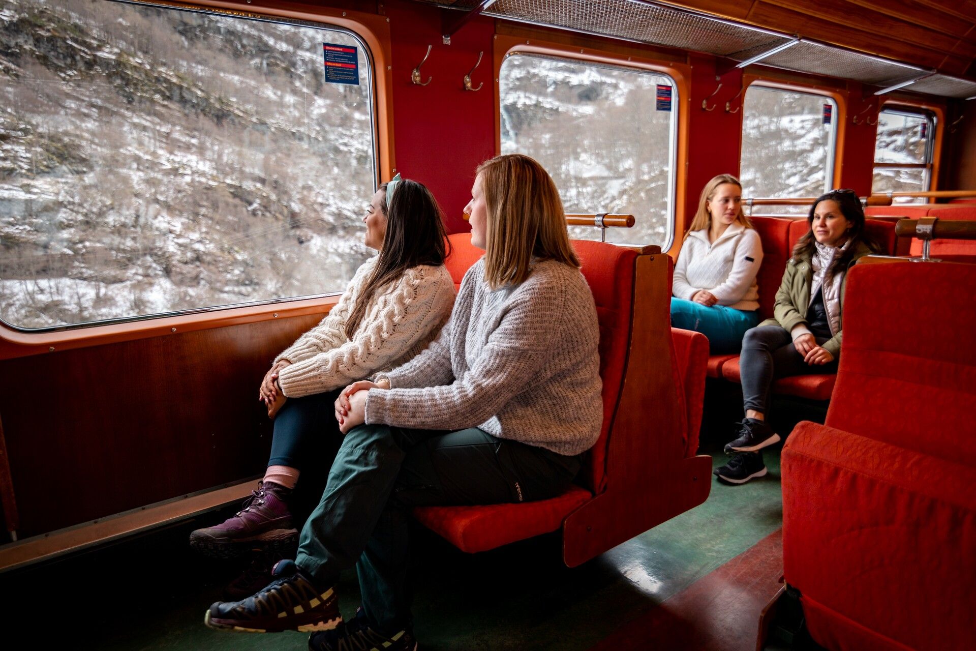 Passengers on the Flåm Railway looking out of the large train windows.