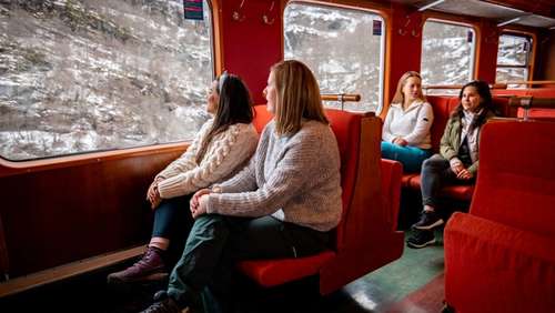 Passengers on the Flåm Railway looking out of the large train windows.