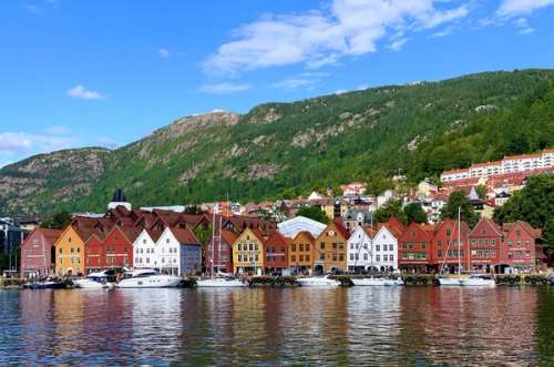 Colorful wooden houses on a pier in front of a ridge and blue sky
