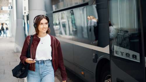 Girl with headphones in front of bus